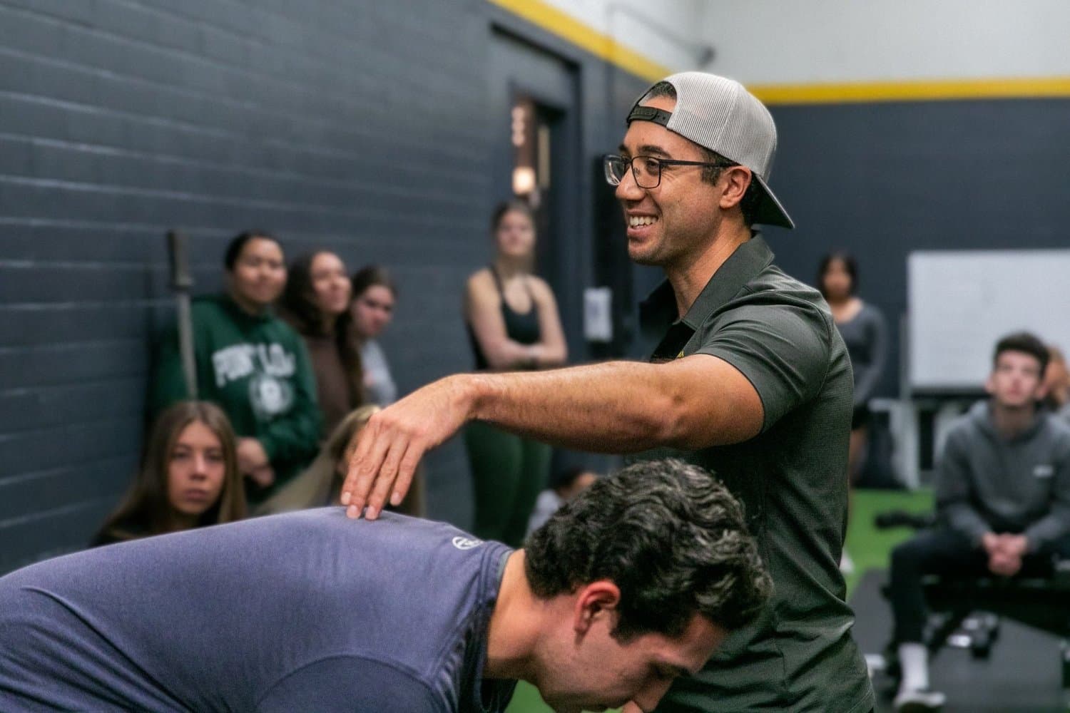 Dr. Jacob Goodin coaching a barbell lift in the university weight room