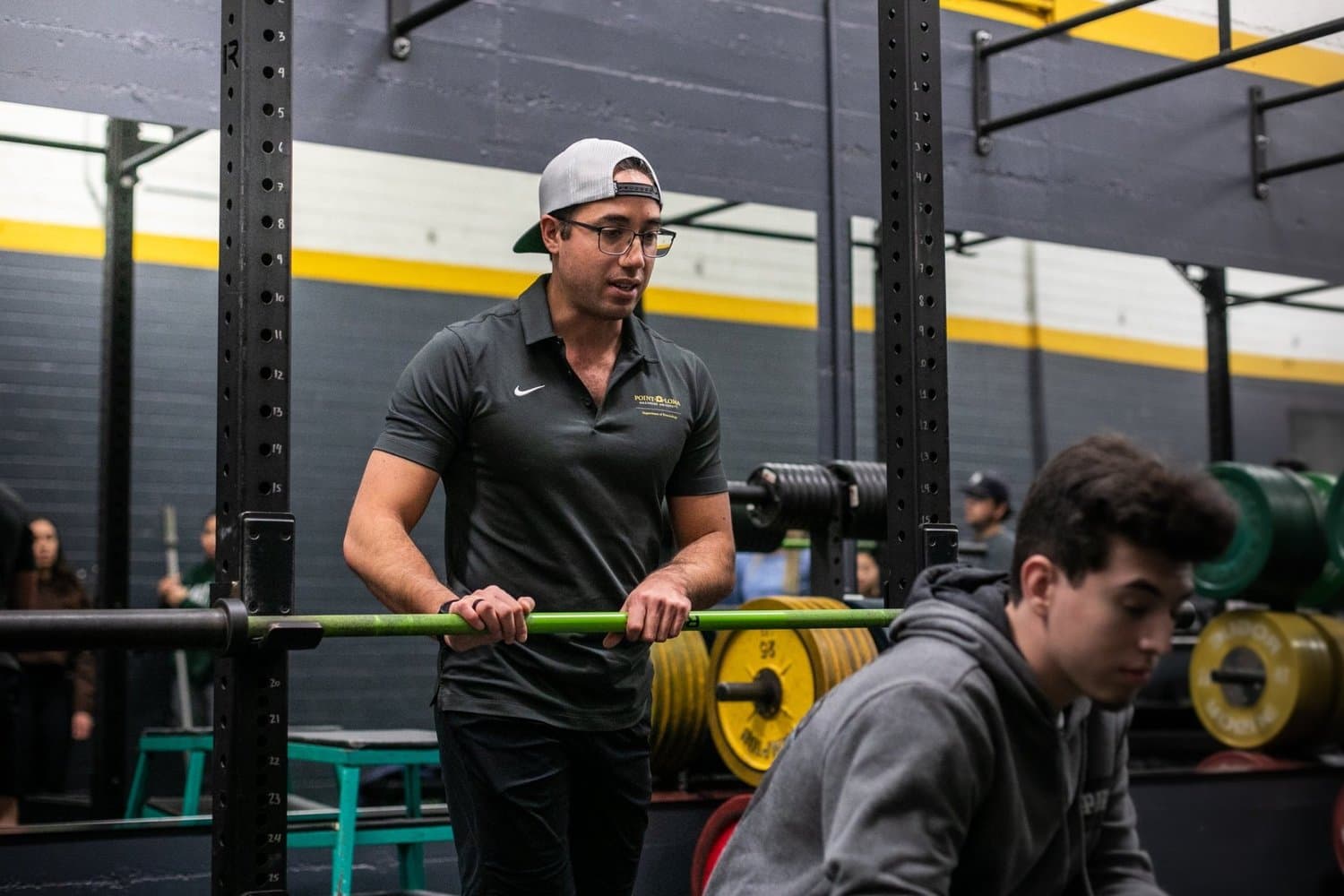 Dr. Jacob Goodin coaching a lift in the university weight room